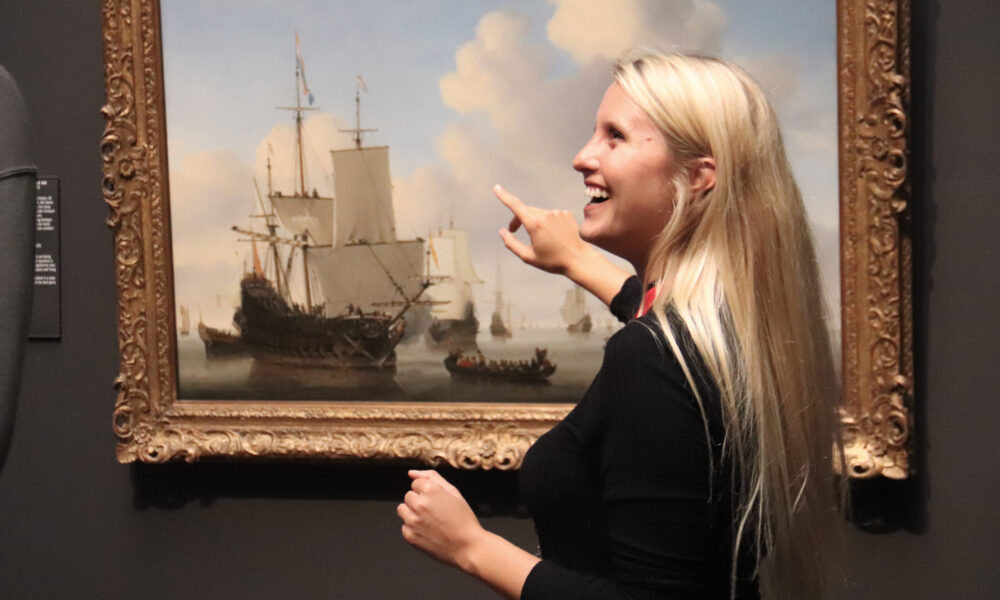 Blonde woman looking at old Dutch painting. Art in Amsterdam.