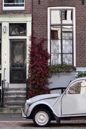 A vintage white car parked on a quiet street in Amsterdam. The car is a classic model.