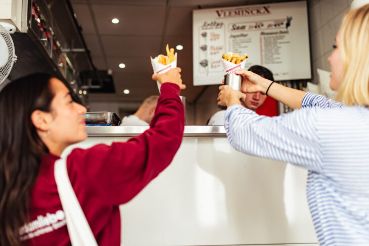 Two women enjoying ice cream in Amsterdam. They are smiling and toasting their ice cream cups.