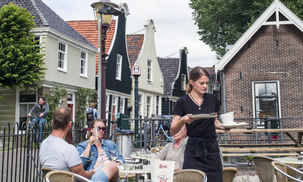 Tourteilnehmer der Amsterdamliebe Fahrradtour Noord sitzen gemütlich auf der Terrasse des Café t'Sluisje