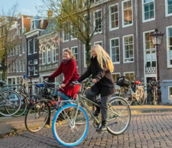 Amsterdamliebe Innenstadt Fahrradtour Tourguide Vera radelt mit einer Tourteilnehmerin über eine Brücke