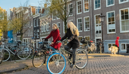 Amsterdamliebe Innenstadt Fahrradtour Tourguide Vera radelt mit einer Tourteilnehmerin über eine Brücke