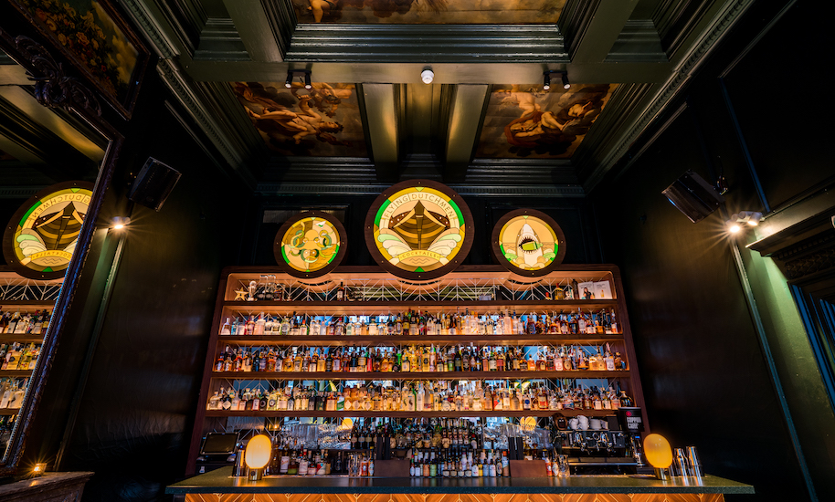 Dunkle Theke der Cocktailbar Flying Dutchman in Amsterdam mit einer Wand voller Flaschen, um gute Cocktails zu mischen.