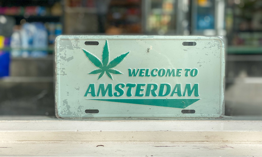 Grünes "Welcome in Amsterdam"-Schild mit Hanfpflanze.