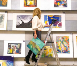 A woman hanging a piece of art. Amsterdam art scene.