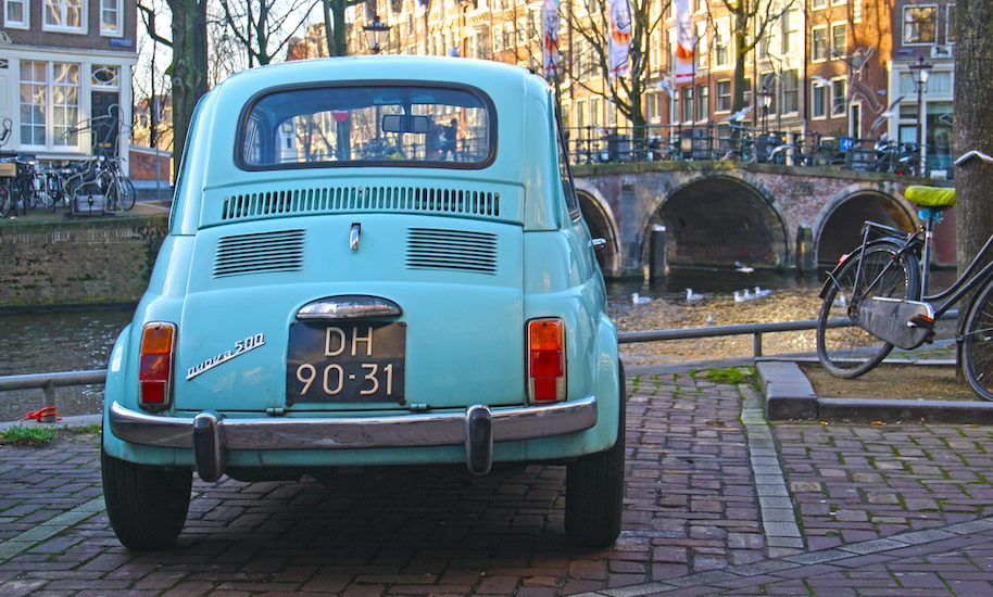 Ein parkender hellblauer Fiat 500 im Amsterdamer Grachtengürtel