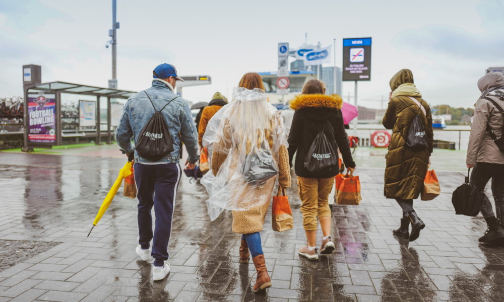 People walking on a wet pavement with rain gear. Tourists exploring Amsterdam on a rainy day.