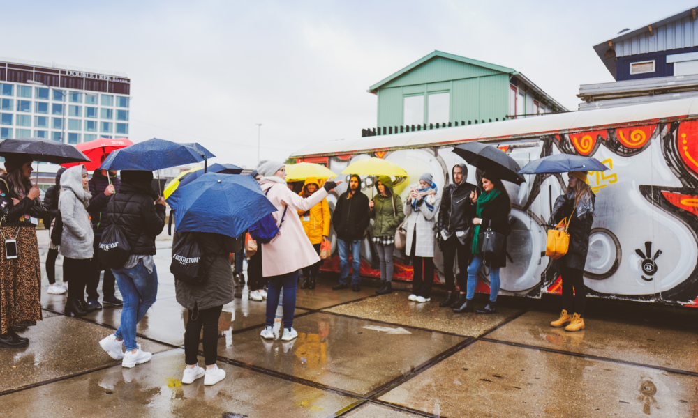 People standing under umbrellas on a rainy day. A group of tourists on a city trip.
