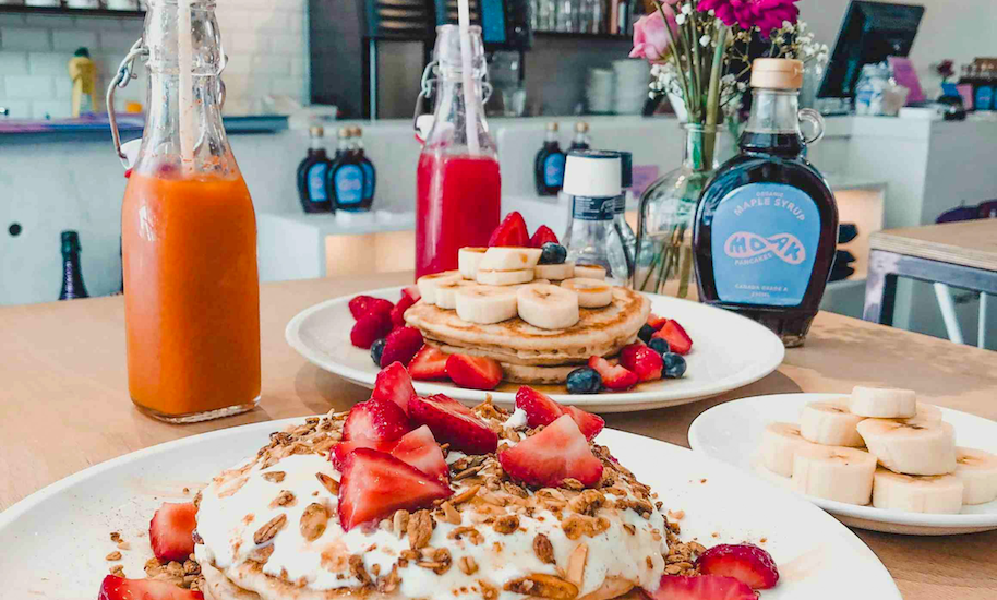 Pancakes with strawberries and whipped cream on a plate. Tasty breakfast in a cafe.