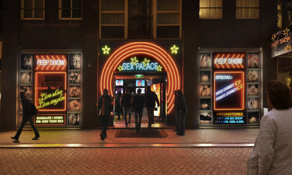 The exterior of the Sexmuseum in Amsterdam at night. People walking towards the entrance