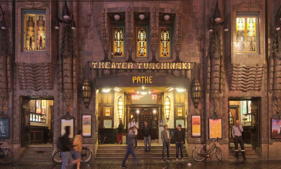 Theater Tuschinski building exterior at night. People walking by.