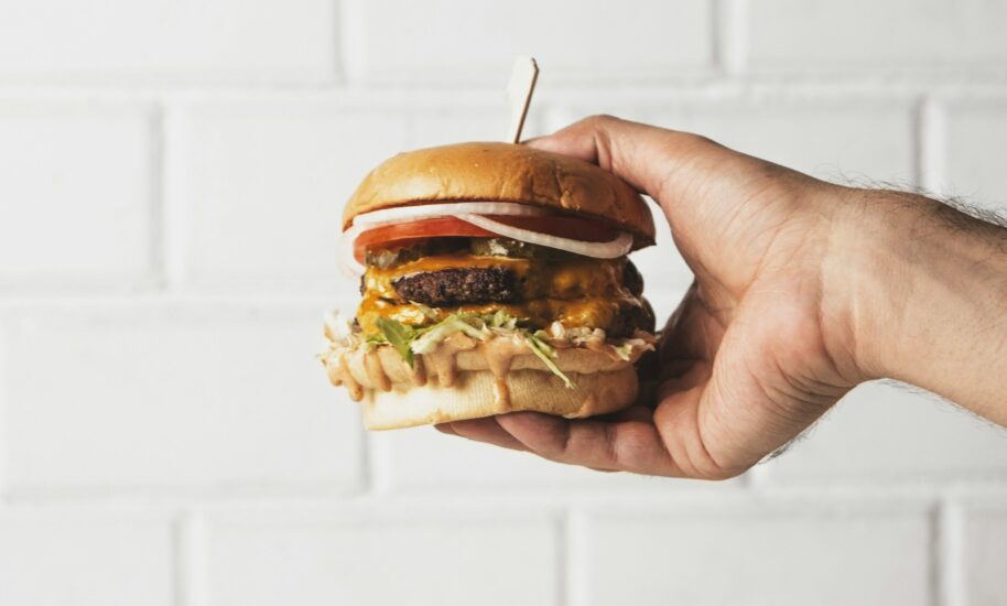 A hand holding a burger. The burger looks delicious.