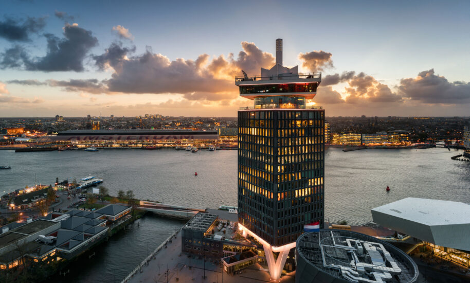 illuminated tower in Amsterdam Marina at sunset. A city skyline with a large body of water