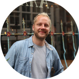 Man smiling in front of a fence.