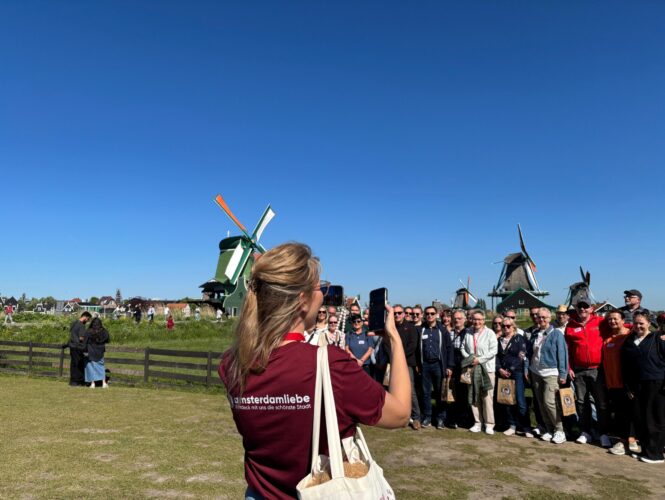 Tour guide Theresa taking a photo of a tour group in front of Zaansche schans windmills.