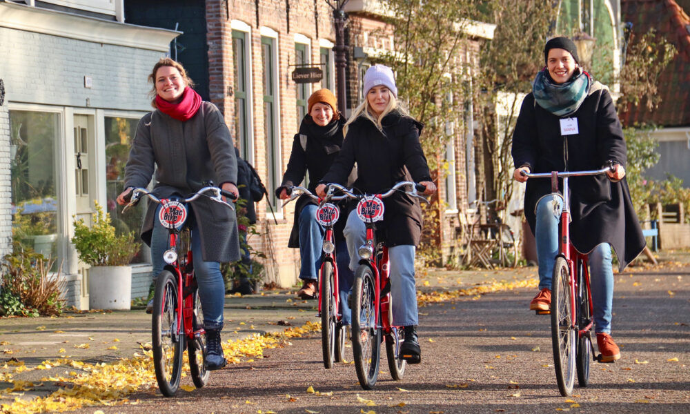 Group of tourists on bicycles in Amsterdam. People enjoying a bike tour on a sunny autumn day.