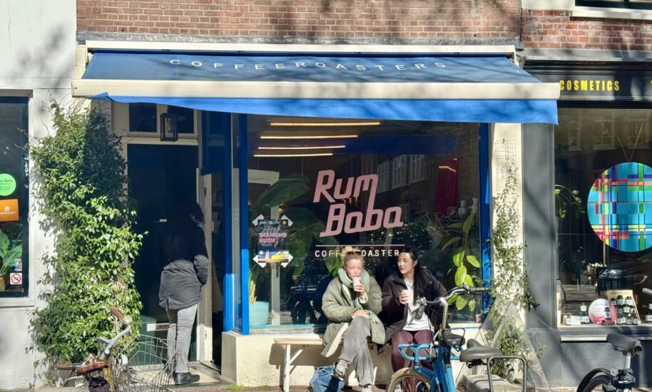 The Café Rumbaba in the Elandsgracht. A blue awning cafe with people sitting outside. A bike is parked in front.