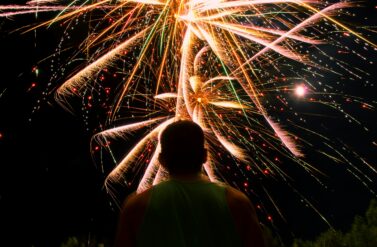 fireworks behind a man facing his back