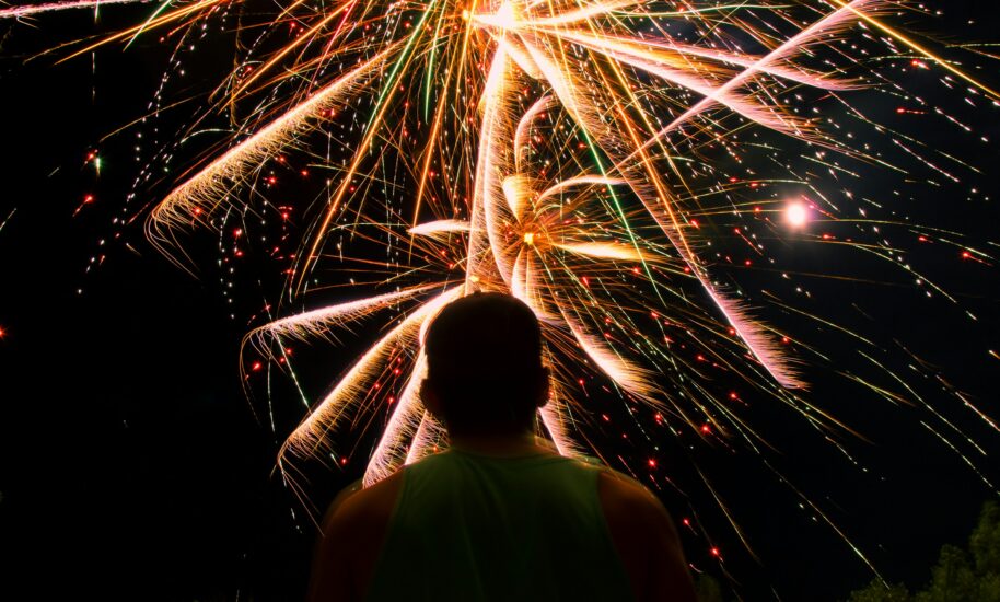 fireworks behind a man facing his back