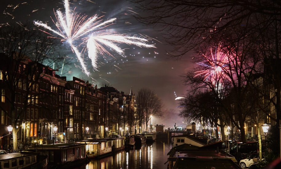 Fireworks exploding over a canal in Amsterdam. A beautiful nighttime scene.