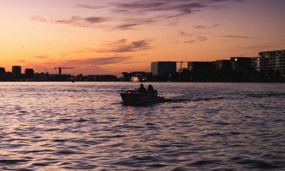 Silhouette of a boat on a river with buildings in the background. Amsterdam cityscape at sunset.