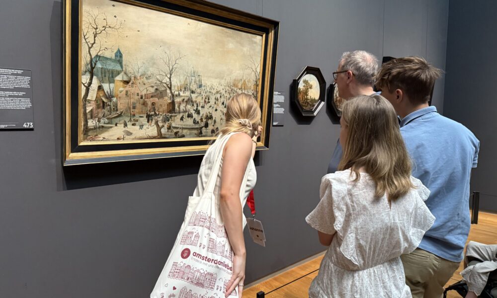 People looking at painting in a museum. The scene shows a typical Amsterdam tourist experience.
