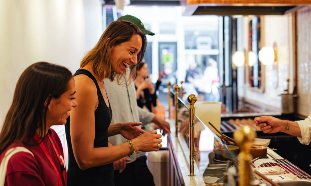 Two women at a coffee shop. They are looking at a menu.
