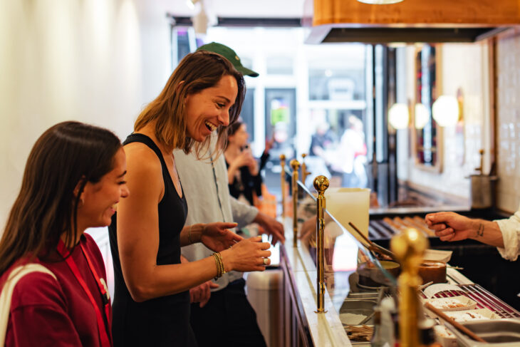 Two women at a coffee shop. They are looking at a menu.