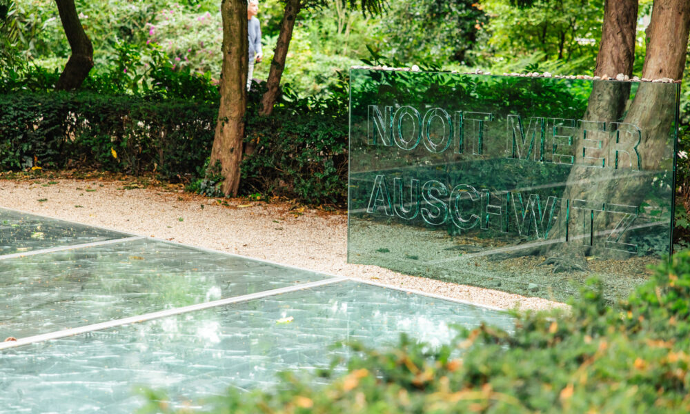 A picture of the Anne Frank House in Amsterdam. A commemorative plaque on a glass wall.