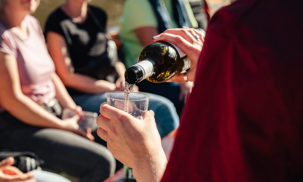 person pouring wine into a glass, people sitting in background. A moment of relaxation in Amsterdam.