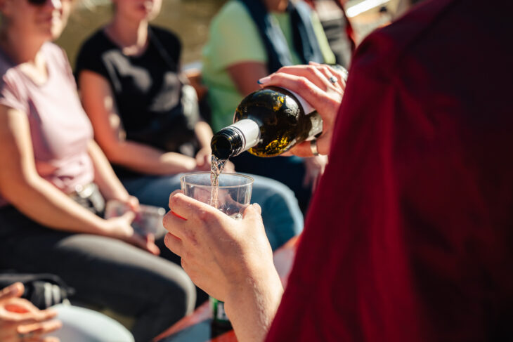person pouring wine into a glass, people sitting in background. A moment of relaxation in Amsterdam.