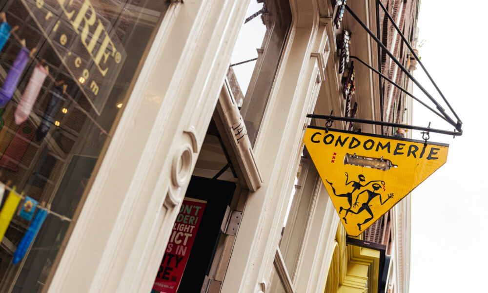 A yellow triangular sign for Condomerie shop. A historic shop in Amsterdam.