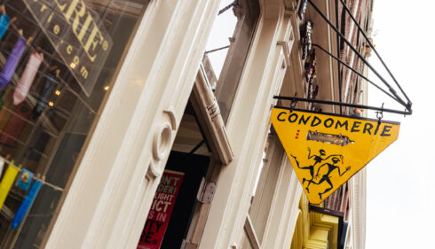 A yellow triangular sign for Condomerie shop. A historic shop in Amsterdam.