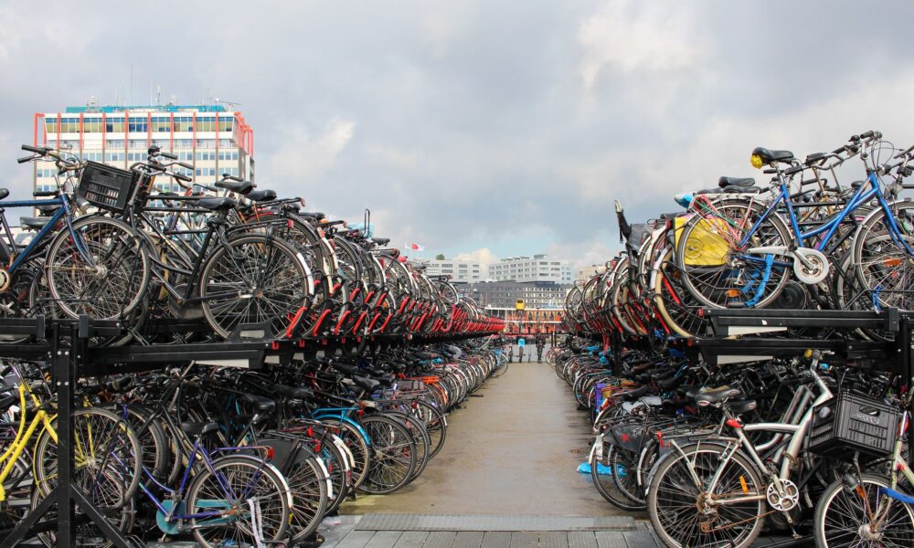 A large parking lot filled with bicycles of various colors. The bikes are neatly arranged on multiple levels of racks.