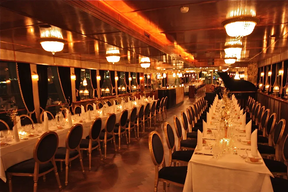 A luxurious restaurant with long tables set for dinner. Soft lighting and elegant decor create a sophisticated ambiance.