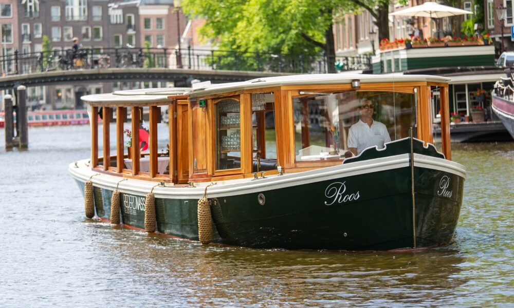 A boat tour on the Amsterdam canal. A green boat with wooden panels