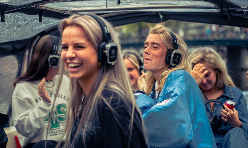 Women wearing headphones on a tour bus. They appear to be on a guided tour.