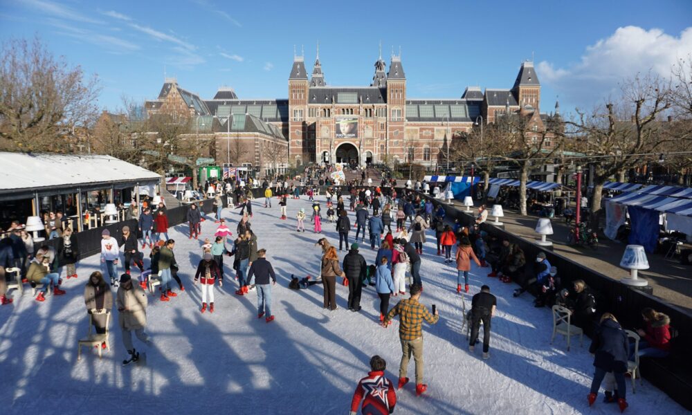 People ice skating in front of a large building. A fun winter activity in Amsterdam.
