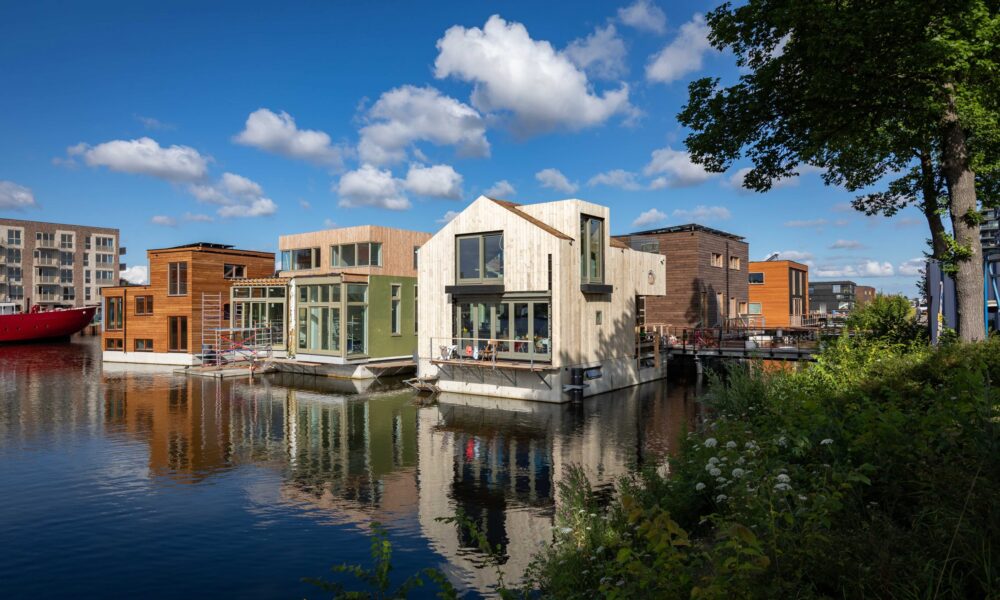 Image of modern houses on a canal in Amsterdam. A serene view of Amsterdam's unique housing.