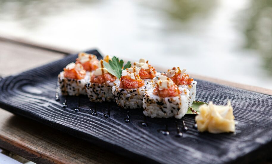 Delicious sushi rolls on a black plate. A small piece of ginger on the side.