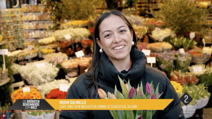 Smiling woman holding tulips. Colorful flowers on display.