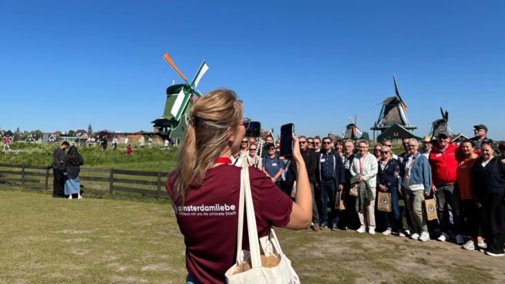 Woman taking a photo with her phone. A group of people are standing next to her.