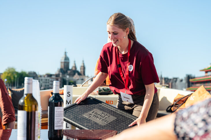 Tour guide from Amsterdamliebe on a boat tour, preparing to hand out drinks for guests.