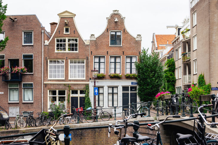 Traditional Dutch houses and boats by a canal. Amsterdam cityscape.