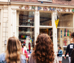 A group of tourists on a tour through the Red Light District. They are standing in front of the Condomerie, a famous shop in Amsterdam.