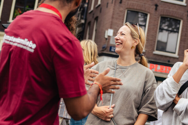 Tour guide in red shirt talking to smiling tourists