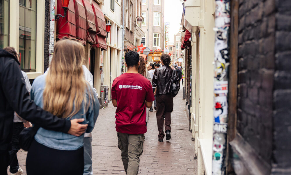 Couple and friends walking down a street in Amsterdam. Colorful buildings and brick pavement.