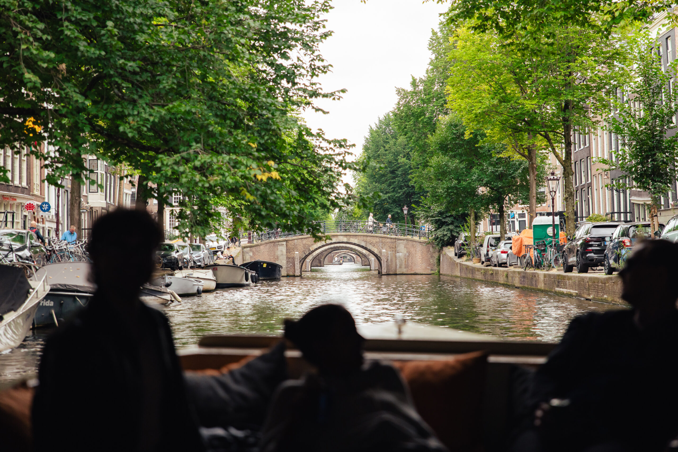 People on a boat looking at a canal bridge. A typical Amsterdam city view.
