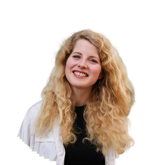 A smiling blonde woman on a city trip. She has long, curly hair.