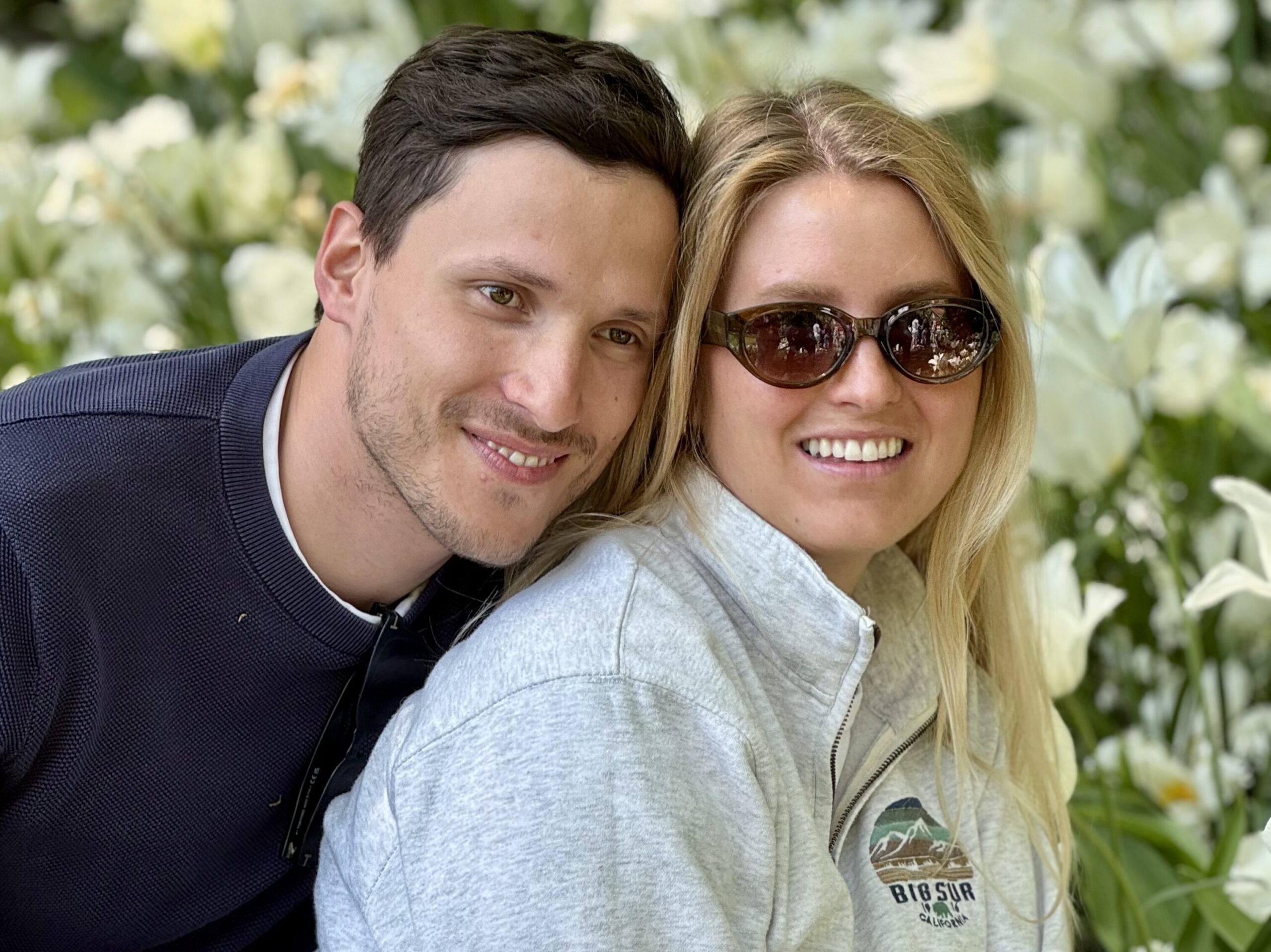 A man and woman embracing in a beautiful garden. They are smiling and enjoying each other's company.